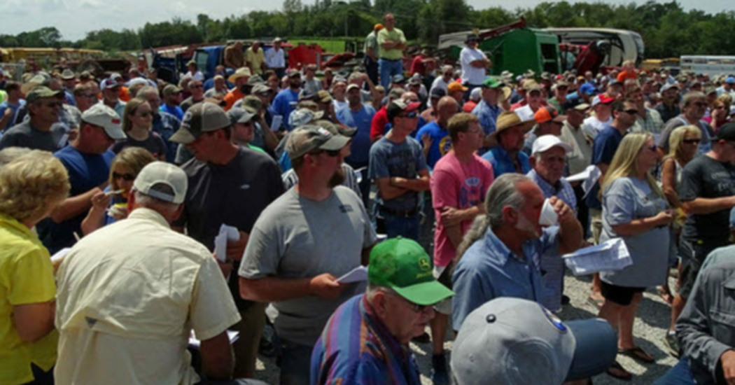 farmers stand in silence at auction